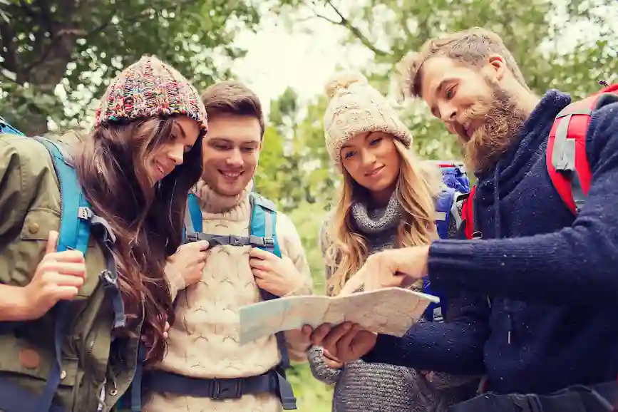 Group of friends with backpacks reading a map during a hike