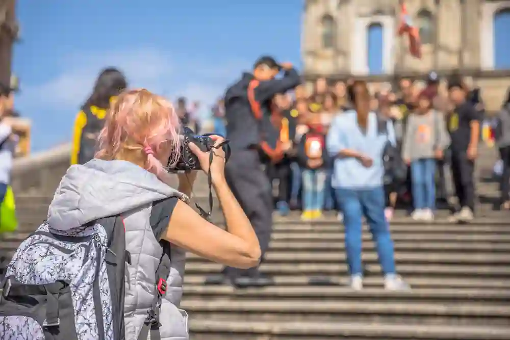 A tourist with blonde hair and a backpack takes a photograph