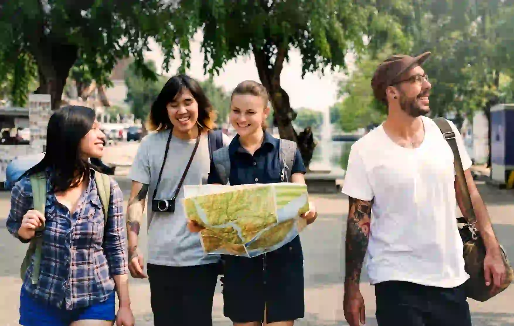 Group of happy backpackers walking outdoors in Chiang Mai, Thailand, with one holding a map while exploring the city together