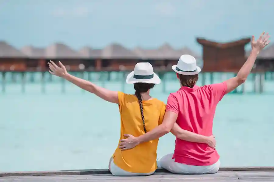 Couple with arms raised in joy sitting together.