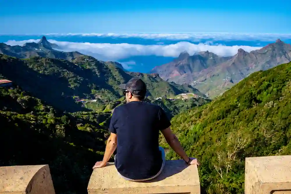 traveler sitting on mountain viewpoint overlooking valley and clouds