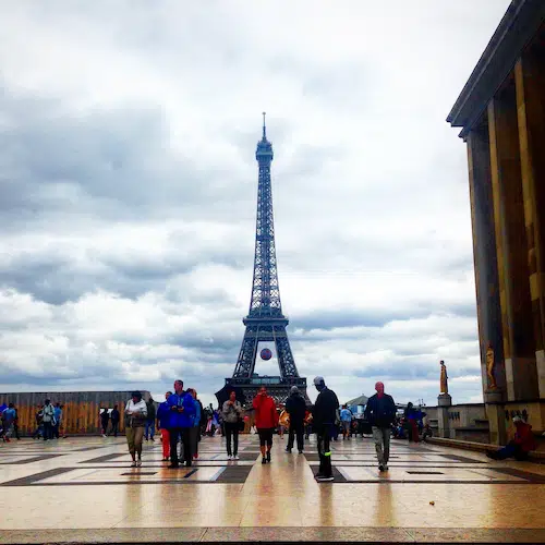The Eiffel Tower in Paris seen from Place du Trocadéro on an overcast, cloudy day with tourists walking across the plaza