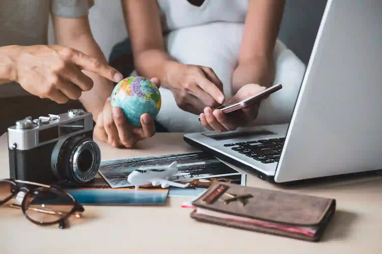 Traveler's hand reaching over a map with travel items while searching for destinations.